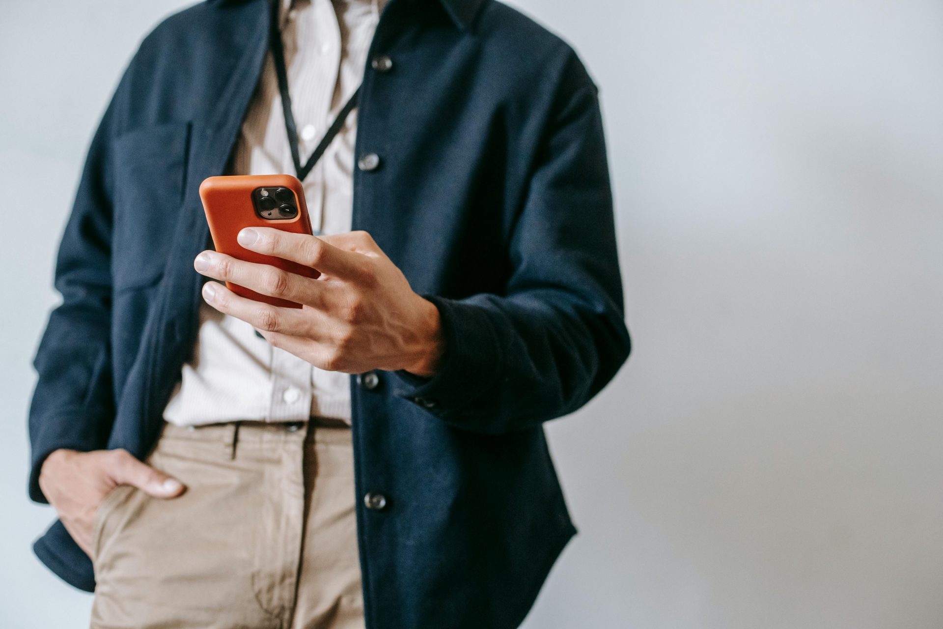 A man in casual attire browsing on a smartphone indoors, showcasing modern tech lifestyle.