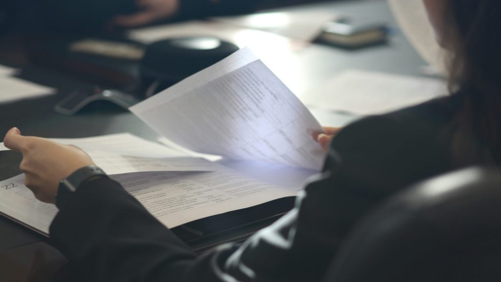 a woman sitting at a table reading a paper
