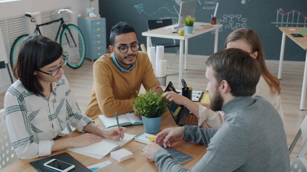 Diverse team collaborates around a table in office.